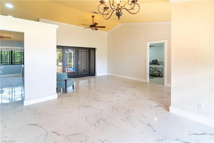 Unfurnished room with crown molding, suspended lighting, a ceiling fan, and lofted ceiling