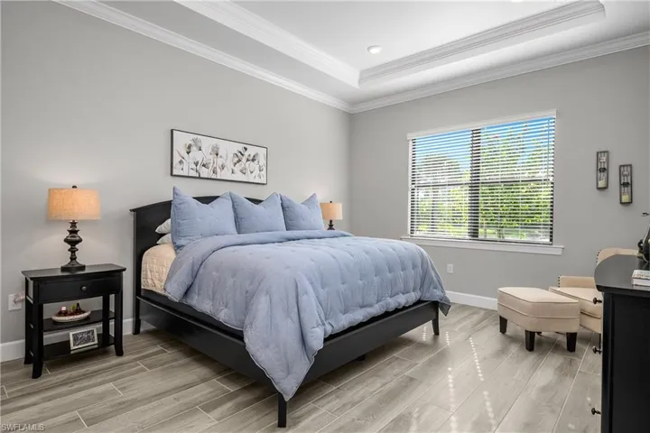 Primary Bedroom is spacious and features crown molding, tray ceilings, tile flooring, and attached spa-like bath and oversized walk-in closet.