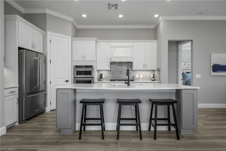Well appointed kitchen features soft touch "leathered" quartz countertops, custom backsplash, upgraded stainless steel appliances, soft close cabinetry with pull-out drawers, spacious pantry, and oversized island for entertaining guests.