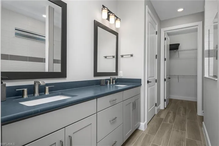Primary Bathroom with soft touch "leathered" quartz countertops, dual sink vanity, oversized walk-in shower with custom tile, and oversized walk-in closet.