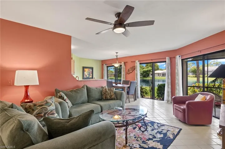 Living room featuring light tile patterned flooring, a water view, and ceiling fan