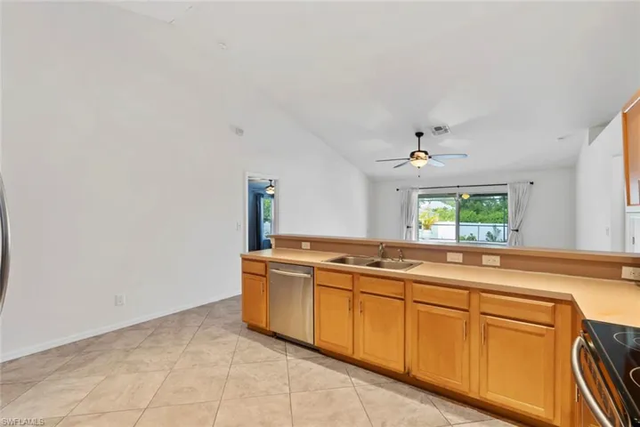 Kitchen with a ceiling fan, visible vents, appliances with stainless steel finishes, vaulted ceiling, and a sink