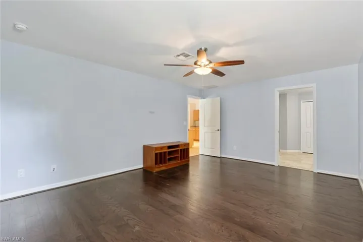 Empty room with visible vents, baseboards, ceiling fan, and wood finished floors