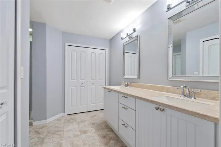 Full bathroom with double vanity, a sink, and baseboards
