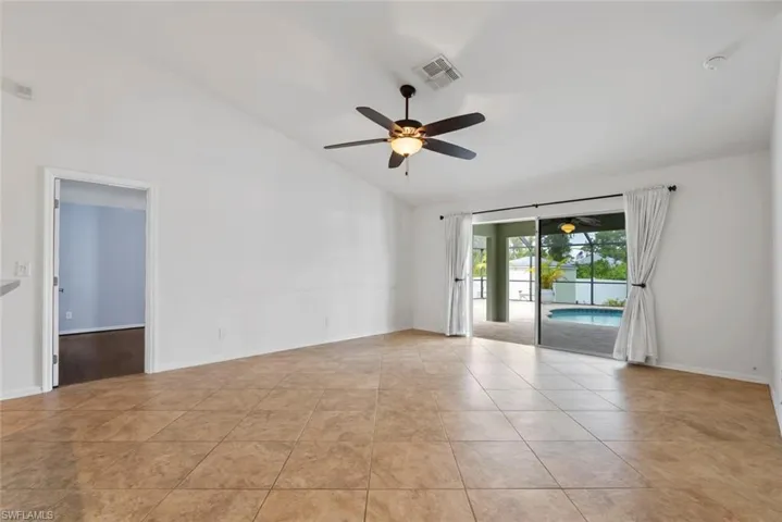 Empty room featuring visible vents, baseboards, high vaulted ceiling, a ceiling fan, and light tile patterned floors