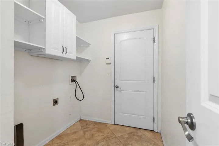 Laundry area featuring cabinet space, hookup for a washing machine, baseboards, light tile patterned floors, and hookup for an electric dryer