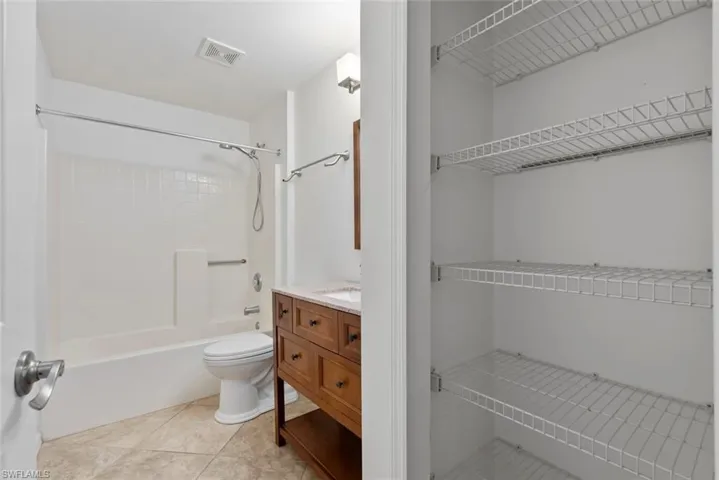 Bathroom with vanity, toilet, tile patterned floors, shower / bathing tub combination, and visible vents