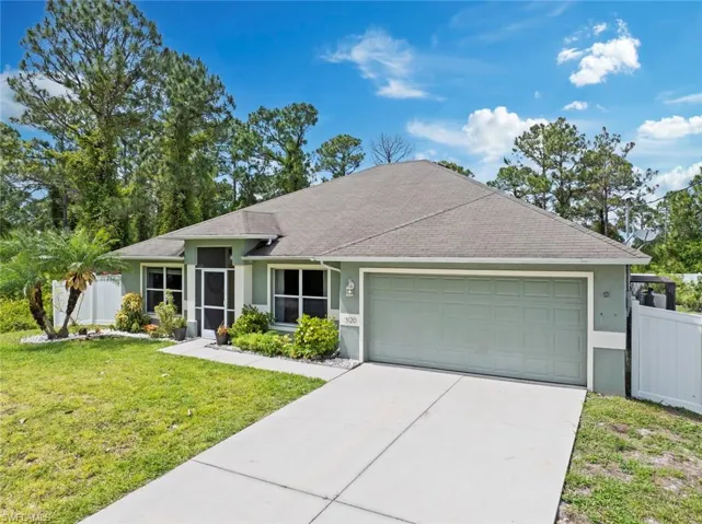 Ranch-style home with driveway, a front yard, fence, an attached garage, and stucco siding