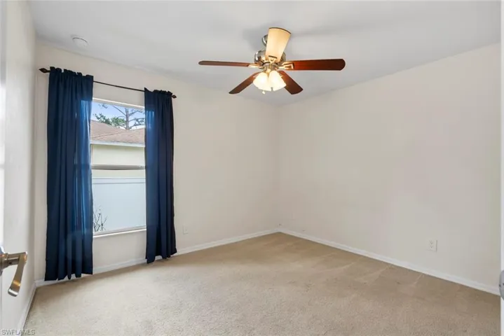 Spare room with ceiling fan, light colored carpet, and baseboards