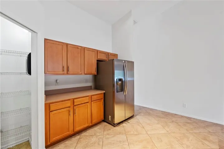 Kitchen featuring brown cabinets, stainless steel refrigerator with ice dispenser, a high ceiling, and light countertops