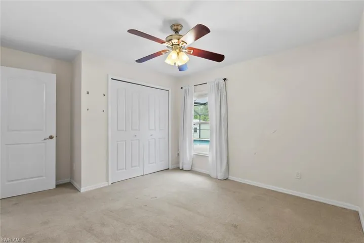 Unfurnished bedroom featuring a closet, carpet flooring, baseboards, and ceiling fan