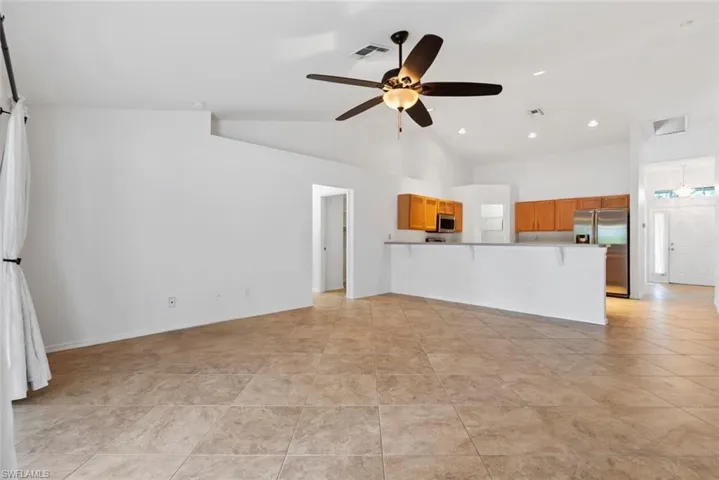 Unfurnished living room featuring vaulted ceiling, a ceiling fan, recessed lighting, and visible vents