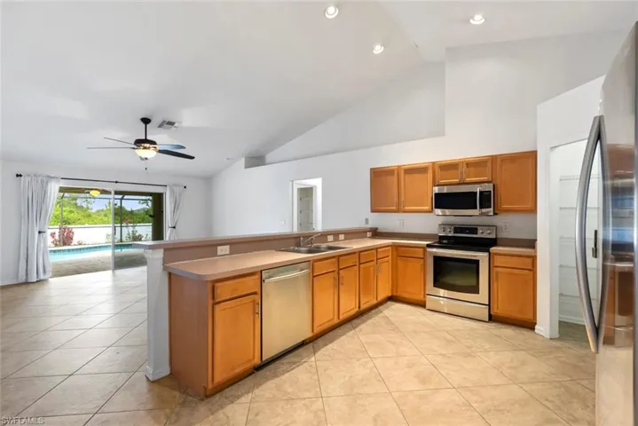 Kitchen with ceiling fan, appliances with stainless steel finishes, a sink, light tile patterned floors, and light countertops
