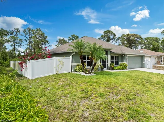 Ranch-style house featuring an attached garage, fence, a front yard, and concrete driveway