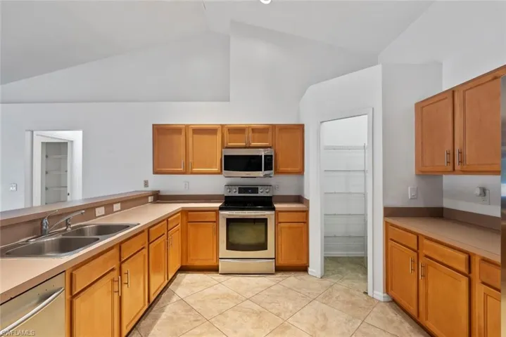 Kitchen featuring light countertops, a sink, light tile patterned flooring, and stainless steel appliances