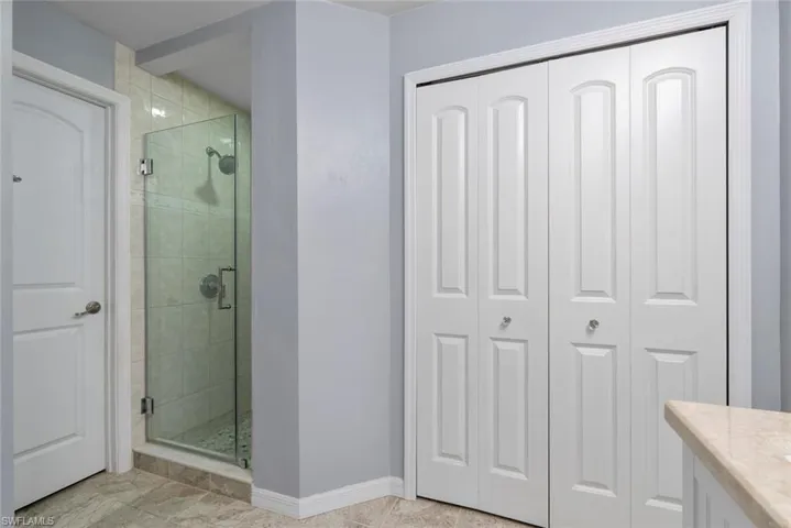 Bathroom with a closet, baseboards, a shower stall, and vanity