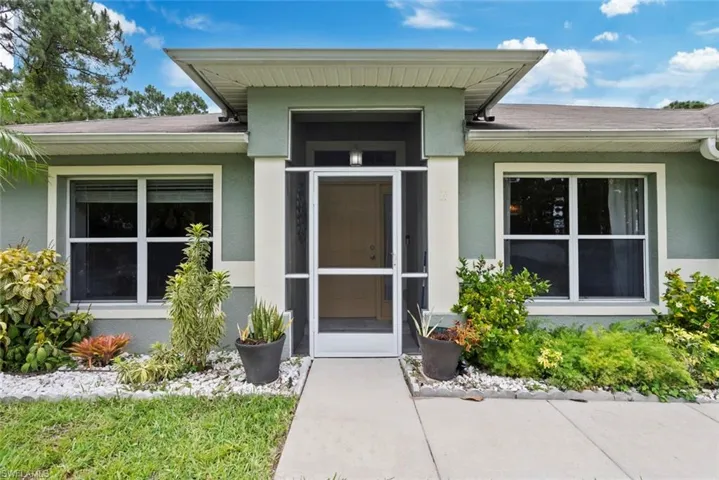 View of exterior entry with a shingled roof and stucco siding