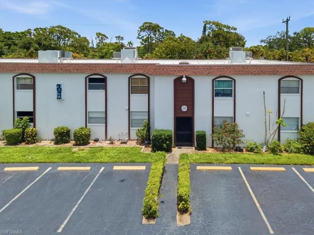 Multi-unit building exterior featuring white stucco finish and brown trim accents
