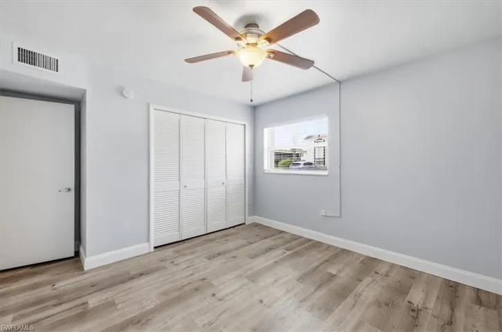 Interior room featuring wood-finish flooring, light blue wall paint, and white baseboards