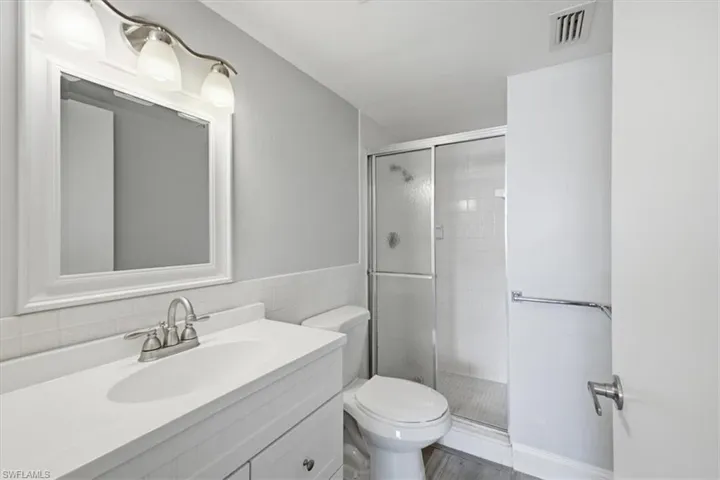 Bathroom featuring a white vanity with integrated sink, brushed nickel faucet, framed mirror, and a three-light fixture