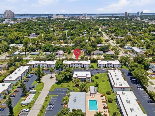Aerial perspective showcasing the multi-building property layout, central swimming pool, multiple parking areas, and mature landscaping