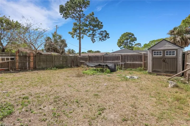 Fenced backyard featuring a storage shed