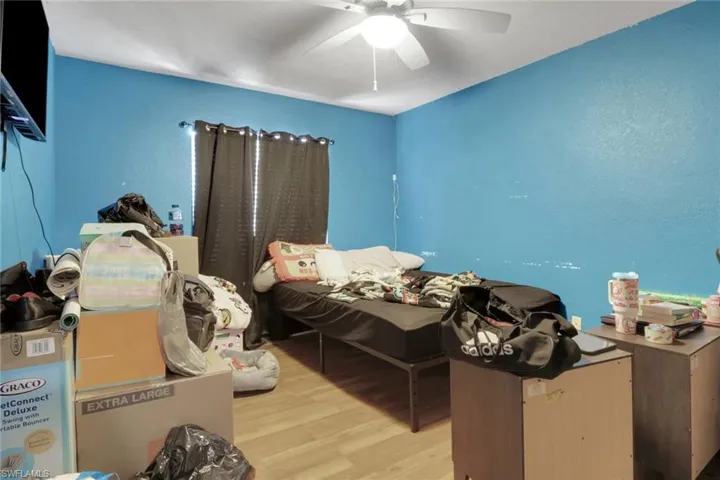 Bedroom featuring light wood-style flooring, a ceiling fan, and a textured wall