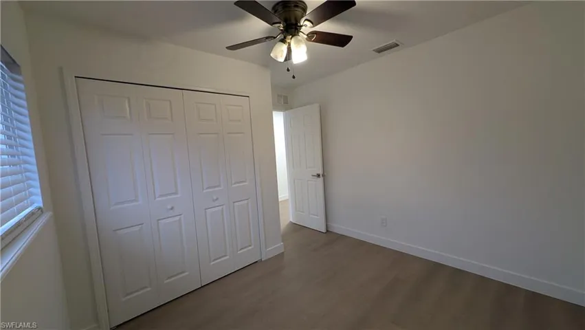 Unfurnished bedroom with dark wood-style flooring, ceiling fan, and a closet