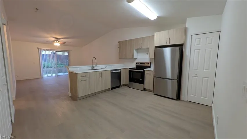 Kitchen featuring light brown cabinets, light countertops, appliances with stainless steel finishes, lofted ceiling, and ceiling fan