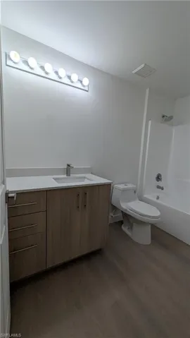 Full bath with vanity, shower / washtub combination, and dark wood-style flooring