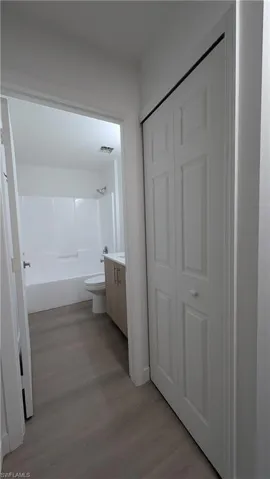 Full bath featuring vanity,  shower combination, light wood finished floors, and a closet