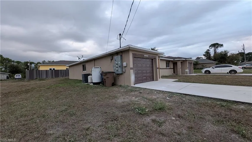 View of side of home with driveway, stucco siding, and a garage