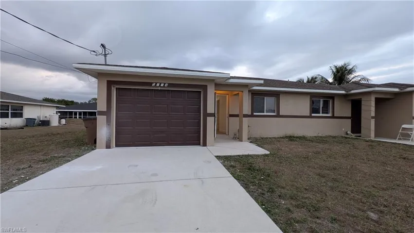 View of front of property featuring concrete driveway, stucco siding, an attached garage, and a front yard