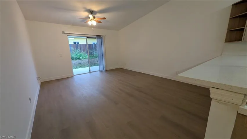 Spare room featuring dark wood finished floors, a ceiling fan, and lofted ceiling