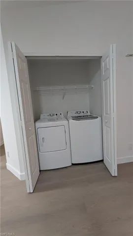 Laundry area featuring washing machine and clothes dryer and light wood-style floors
