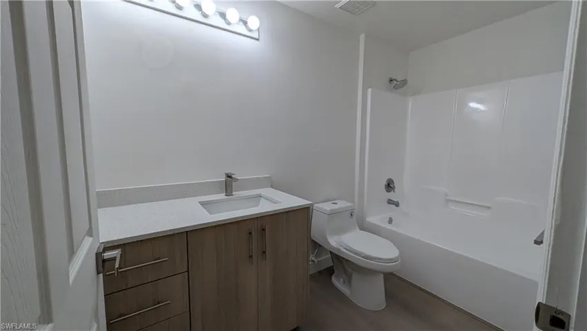 Bathroom with vanity, bathtub / shower combination, and light wood-style floors