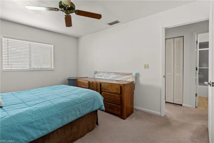 Carpeted bedroom with ceiling fan and baseboards