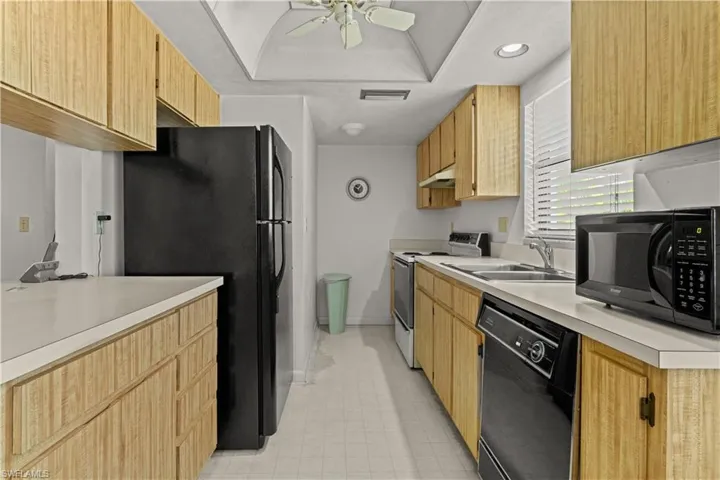 Kitchen featuring black appliances, light countertops, a ceiling fan, and under cabinet range hood