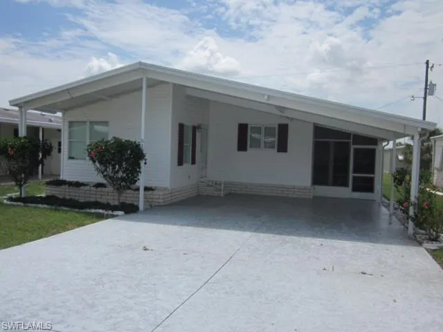 View of front of property featuring concrete driveway and a carport
