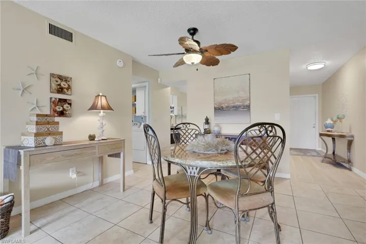 Dining room featuring a textured ceiling, tile patterned flooring, washer / clothes dryer, and a ceiling fan