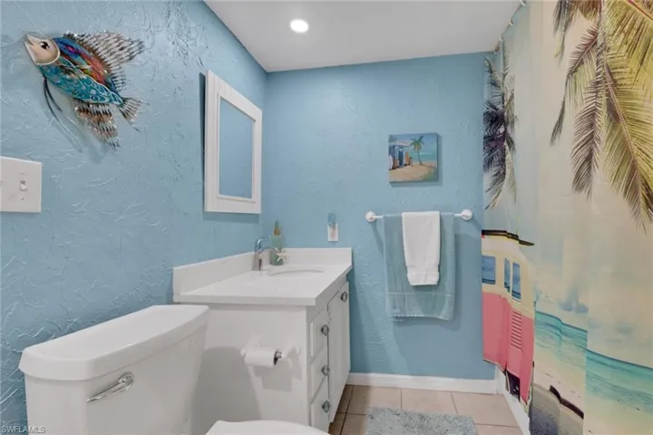 Full bathroom featuring a textured wall, vanity, light tile patterned flooring, recessed lighting, and curtained shower