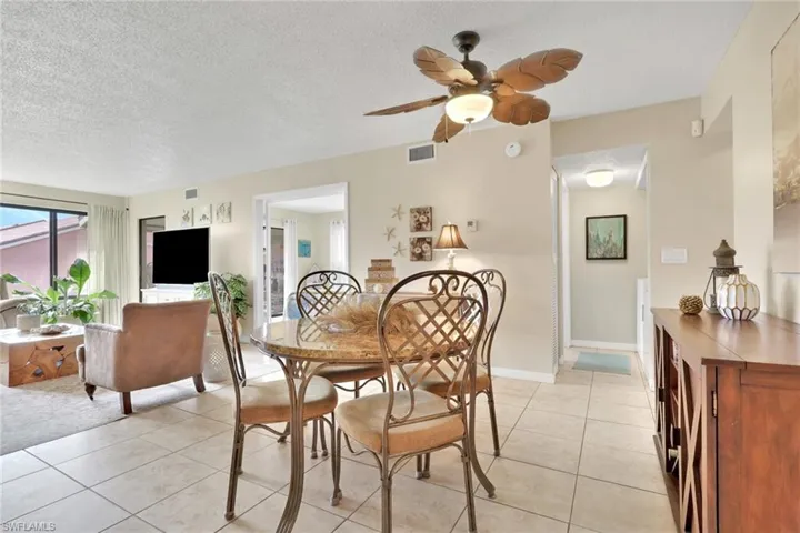 Dining room with a textured ceiling, light tile patterned flooring, and ceiling fan