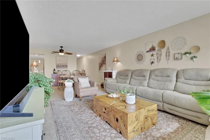Living area featuring a textured ceiling, light tile patterned flooring, and ceiling fan