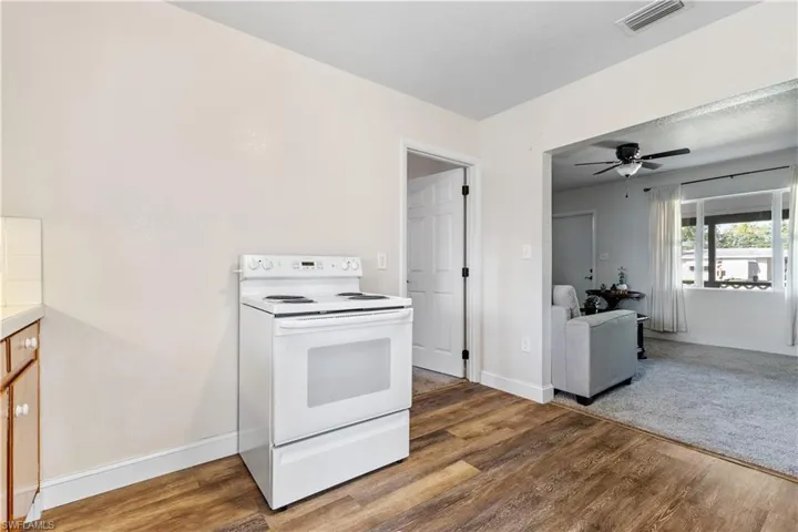 Kitchen with ceiling fan, electric range, and hardwood / wood-style flooring