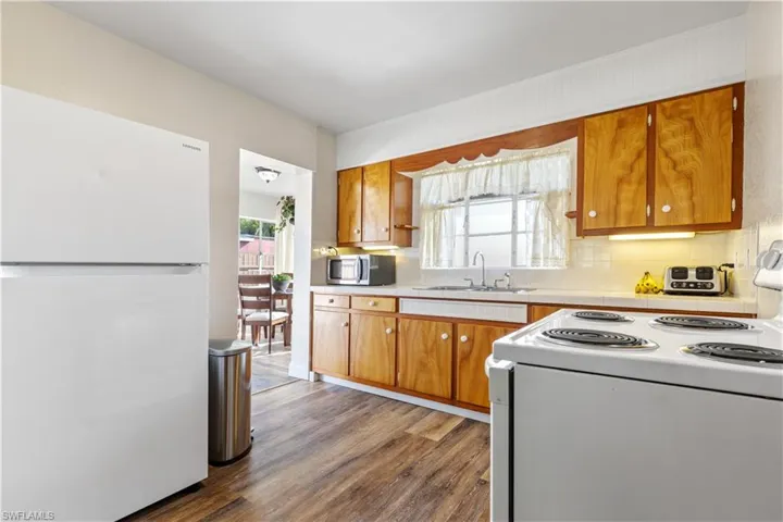 Kitchen featuring sink, wood-type flooring, white appliances, and backsplash