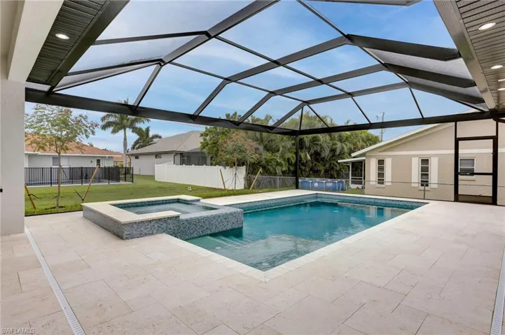 View of swimming pool featuring an in ground hot tub, a yard, a patio, and a lanai