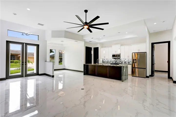 Kitchen featuring appliances with stainless steel finishes, a tray ceiling, decorative backsplash, ceiling fan, and light tile patterned flooring
