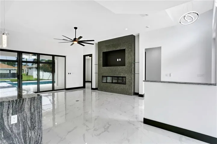 Unfurnished living room featuring tile walls, ceiling fan, a fireplace, and light tile patterned flooring