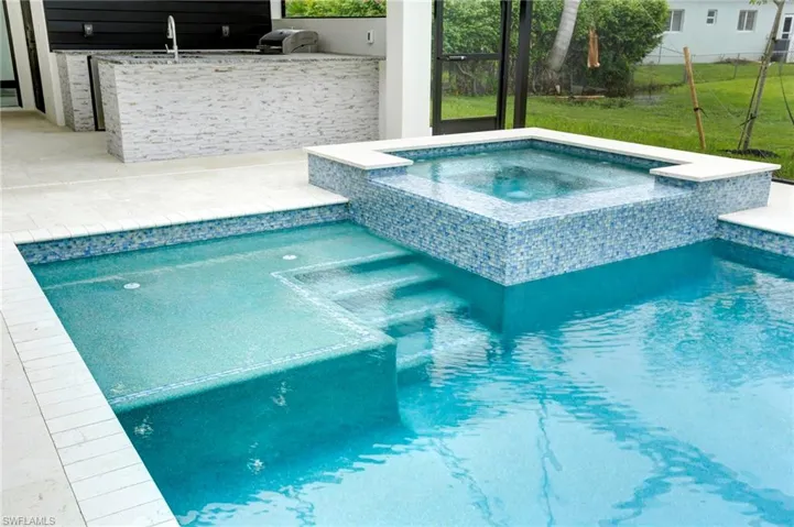 View of pool featuring area for grilling and an in ground hot tub