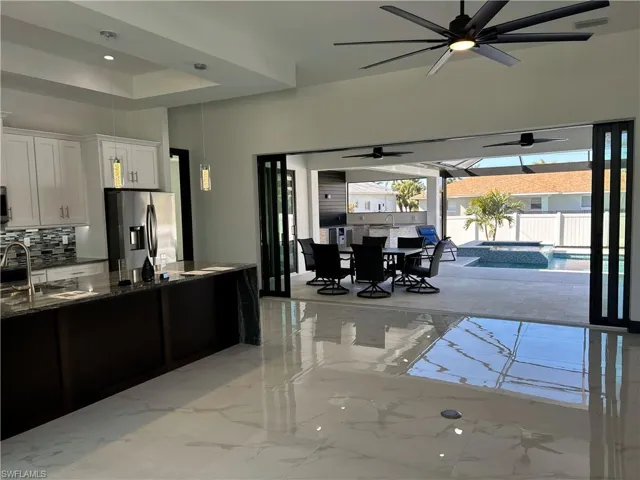 Kitchen featuring sink, stainless steel fridge, dark stone countertops, tasteful backsplash, and white cabinets